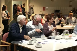Een grote zaal met mensen die met elkaar praten en koffie drinken